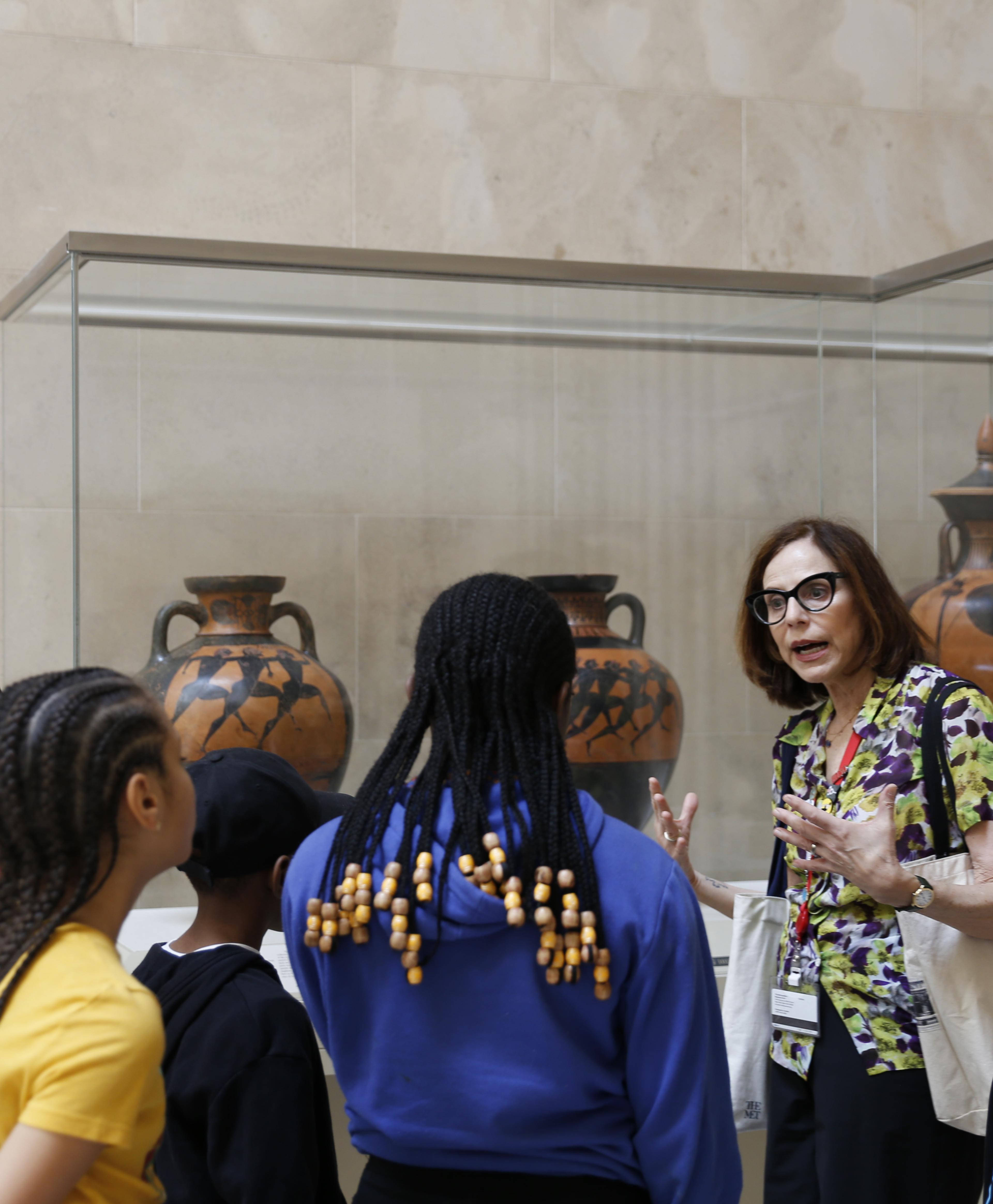 A tour group leader speaks to a group of young people in The Met's Greek and Roman Galleries.